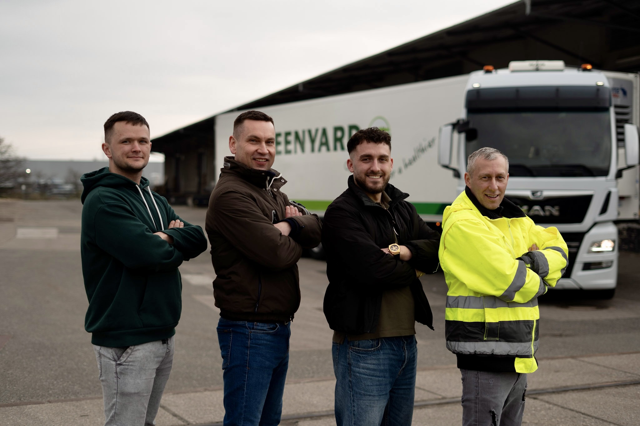 Vier Mitarbeiter von M-Transport vor einem Kühl-LKW
